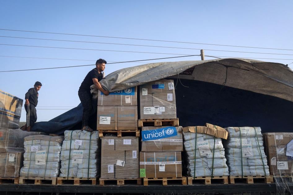 Seorang pria sedang menurunkan bantuan kemanusiaan dari konvoi truk yang memasuki Jalur Gaza dari Mesir melalui perbatasan Rafah pada 21 Oktober 2023. 