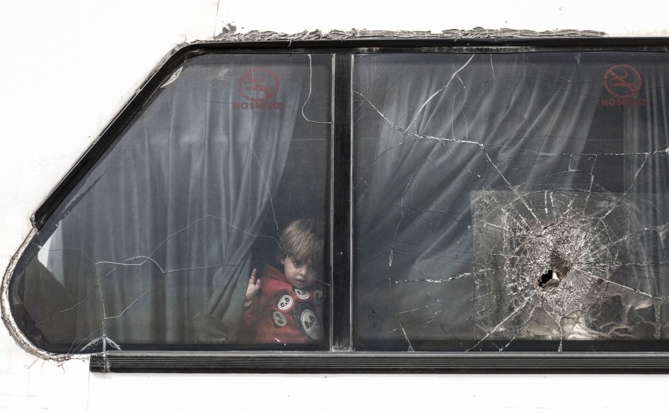 A girl looks through a damaged window pane on a bus