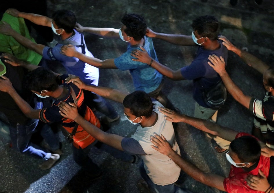 Undocumented migrants walk in line while being detained during an immigration raid in Kuala Lumpur, Malaysia, July 1, 2022.
