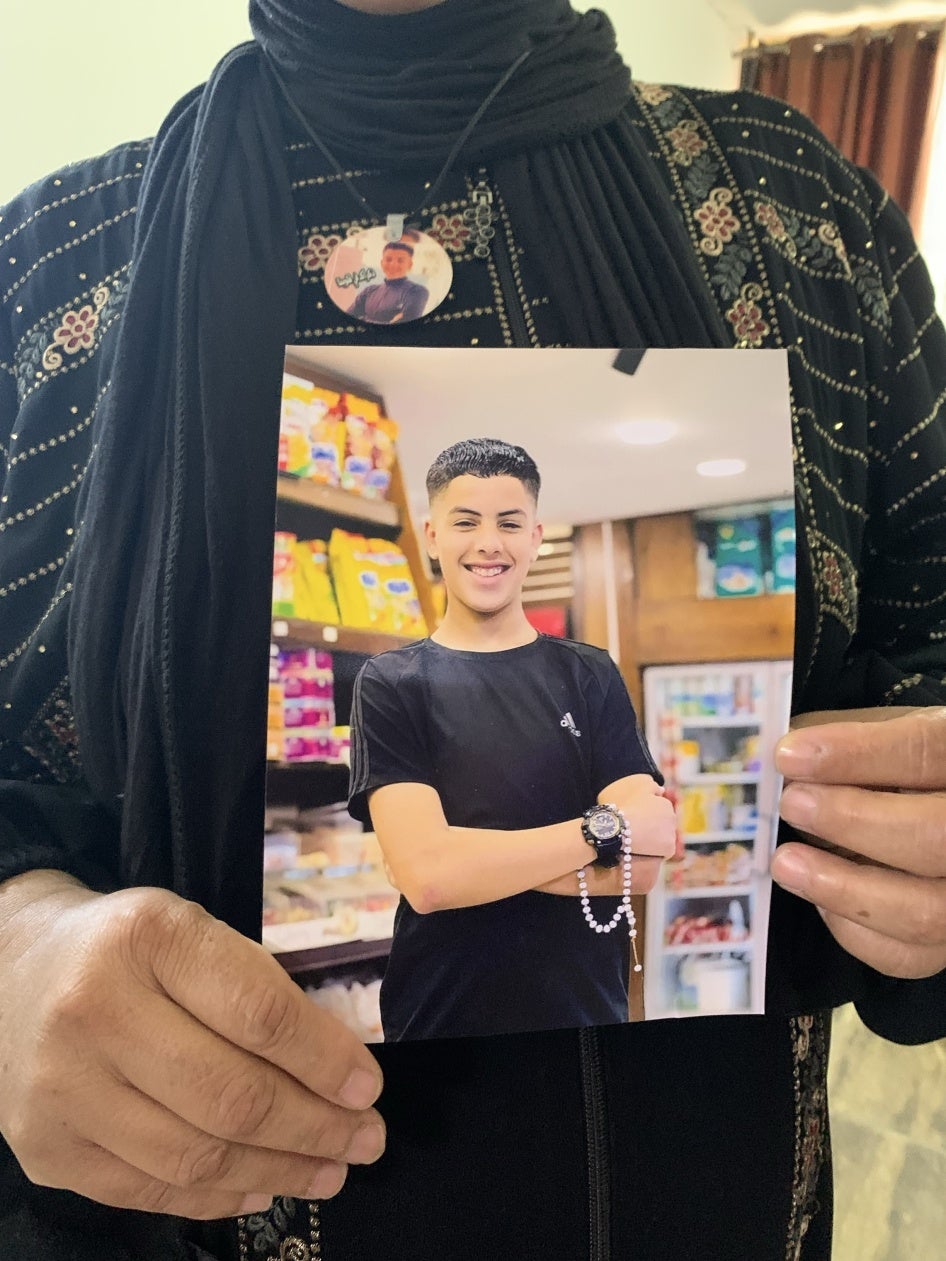 Taha Mahamid’s mother holds a photo of her son, whom Israeli forces killed on October 19, 2023 when he was 15, at the Nur Shams Refugee Camp in the occupied West Bank city of Tulkarem, November 2, 2023. 