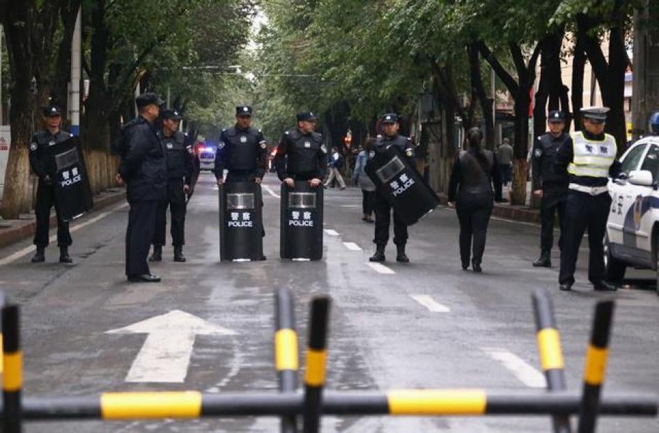 镇暴警察在新疆维吾尔自治区爆裂物攻击现场防守路障，2014年5月23日。