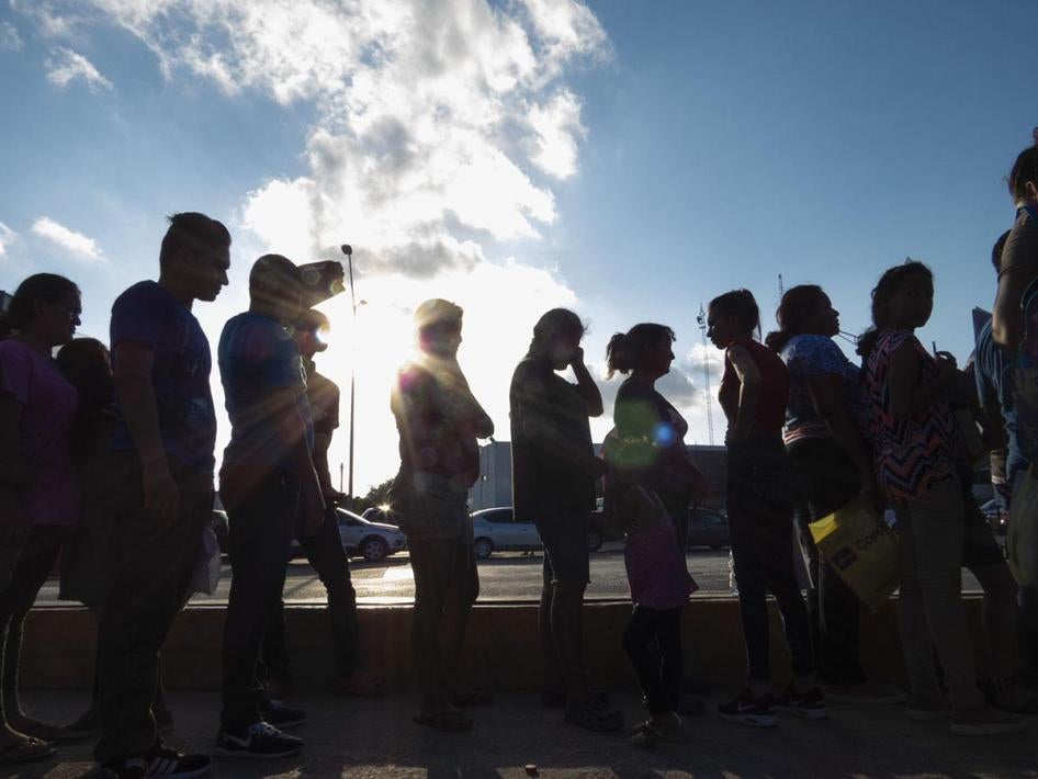 Migrants seeking asylum wait in line with their case paperwork on October 5, 2019