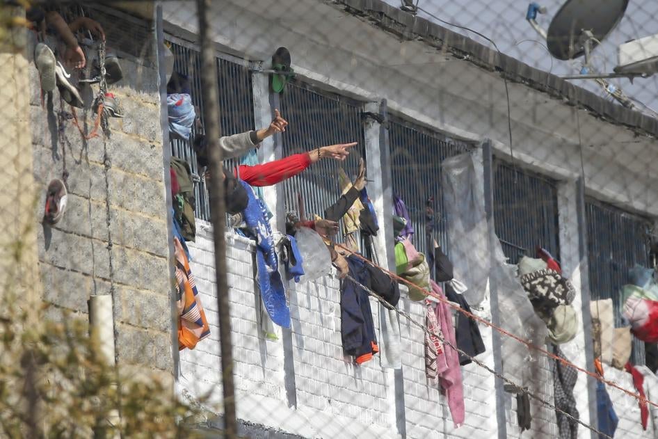 Detentos apontam de dentro da prisão La Modelo em Bogotá, Colômbia, domingo, 22 de março de 2020.
