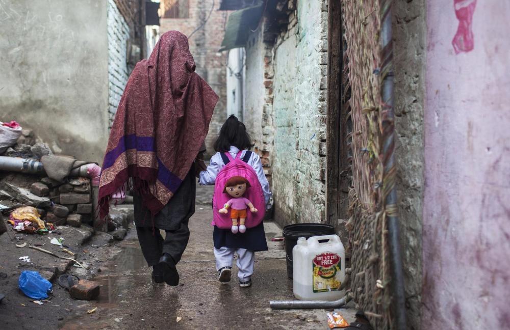 Une mère emmène sa fille à l’école à Islamabad. Les établissements publics sont généralement gratuits, mais les élèves et leurs familles doivent tout de même payer pour leurs uniformes, fournitures et frais d’examen. Ces coûts font que l’éducation est hor