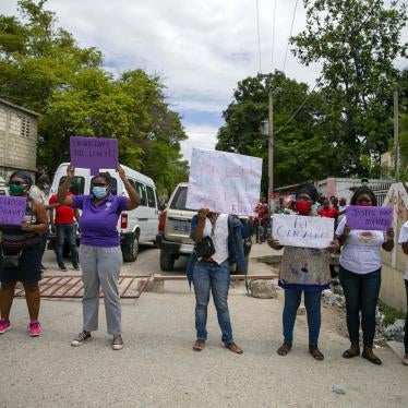 Women hold up signs demanding justice during the hearing of the president of the Fédération Haïtienne De Football (FHF), Yves Jean-Bart, regarding allegations that he abused female athletes at the country's national training center, outside the courthouse in Croix-des-Bouquets, Haiti, Thursday, May 14, 2020.