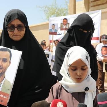Tawfiq al-Mansouri's mother, daughter, and wife hold up a photo of him during a demonstration. Al-Mansouri is one of four imprisoned Yemeni journalists currently facing the death penalty.