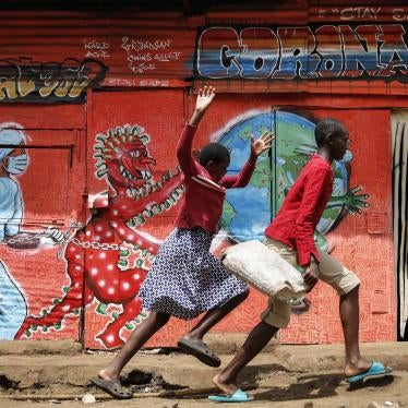 Children run past a mural that warns people about the dangers of the new coronavirus, in the Kibera informal settlement of Nairobi, Kenya.