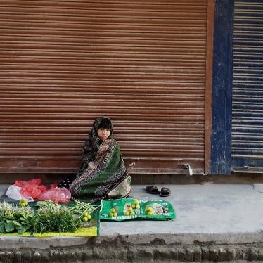A child sits on the sidewalk in front of a display of goods to sell