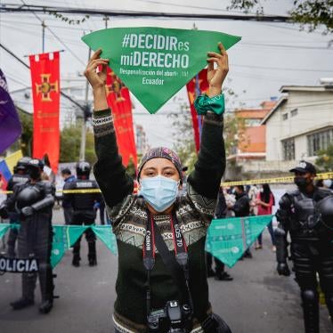 A masked woman in a protest on the street holding up a green flag