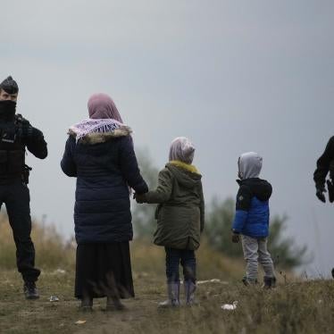 A woman and two children stand in front of two police officers