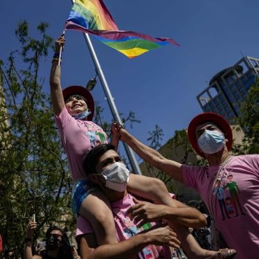 A girl waves a rainbow flag while sitting atop her fathers shoulders