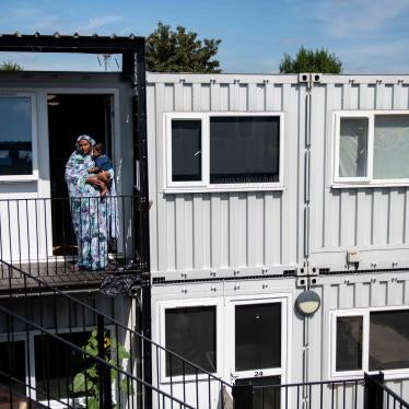 A mother stands with her son outside the front door to their accommodation at a development of converted shipping containers
