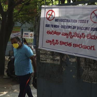 A man in a face mask stands next to a sign that says "No vaccination today" in English and Hindi
