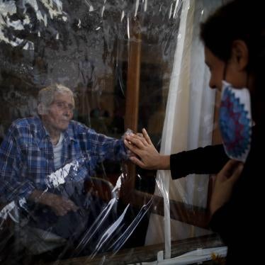 A man and woman touch hands through a plastic sheet