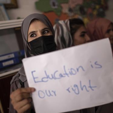 A woman holds a protest sign that reads "Education is our right"