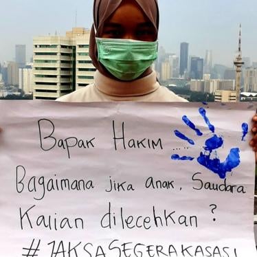 A Universitas Riau student, who accompanied a sexual harassment victim in Pekanbaru, holds a protest sign after the defendant was acquitted. It reads, “Mr. Judge, how would you react to your daughters or sisters being molested?”