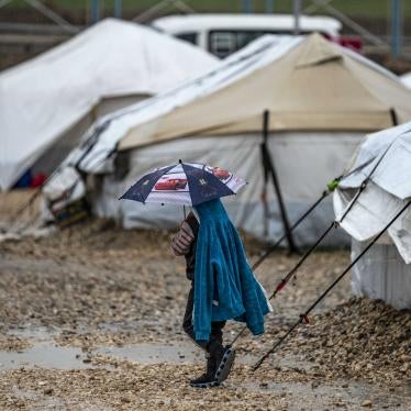 A young person holds an umbrella as he walks in the rain at Camp Roj, where relatives of people suspected of belonging to the Islamic State (IS) group are held, in Syria's northeastern Hasakah province, on March 4, 2021. 