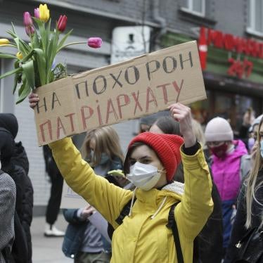 A woman carries flowers and a placard that says "At the funeral of the patriarchy" during the feminist's Women March