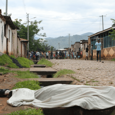 Residents outside their houses in Nyakabiga, in the Burundian capital Bujumbura, look at the body of a man shot dead on December 11, 2015.