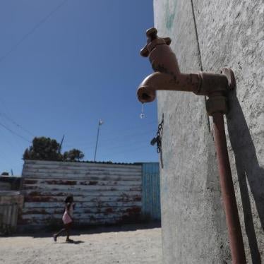 Residents walk past a leaking communal tap in Khayelitsha township, near Cape Town, South Africa, December 12, 2017.