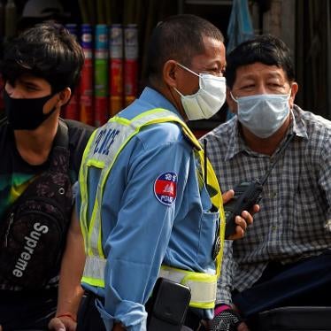 A policeman (center) and others wear face masks as a preventive measure against COVID-19, at a market in Phnom Penh on March 17, 2020.