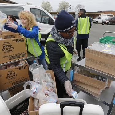School workers load food packs as they distribute meals to students at Fairfield Middle School in Richmond, Virginia, March 18, 2020.